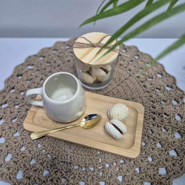 Mesa posta com caneca, tábua de bambu e suspiros sobre sousplat de crochê