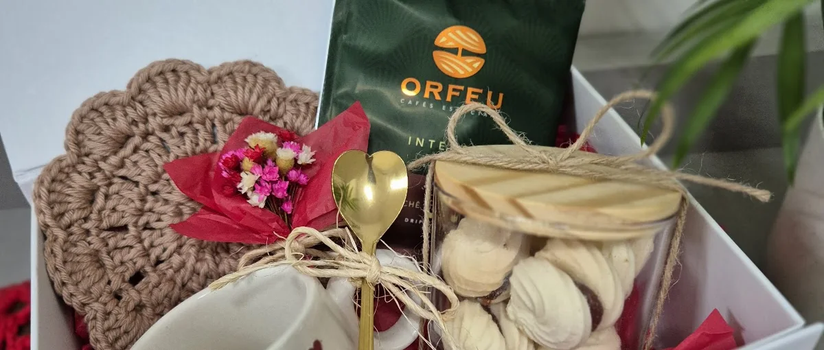 Kit presente em caixa branca com caneca de corações, colher dourada, pote de suspiros, café Orfeu, flores secas e descanso de crochê
