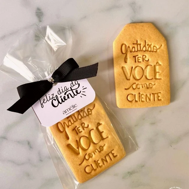 Bolacha amanteigada com a frase "Gratidão por ter você como cliente", embalada com laço preto e tag