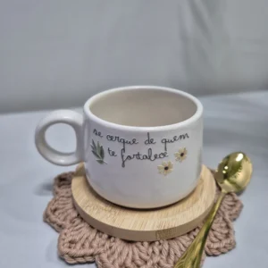 Caneca branca com frase personalizada, colher dourada e descanso de copo em crochê