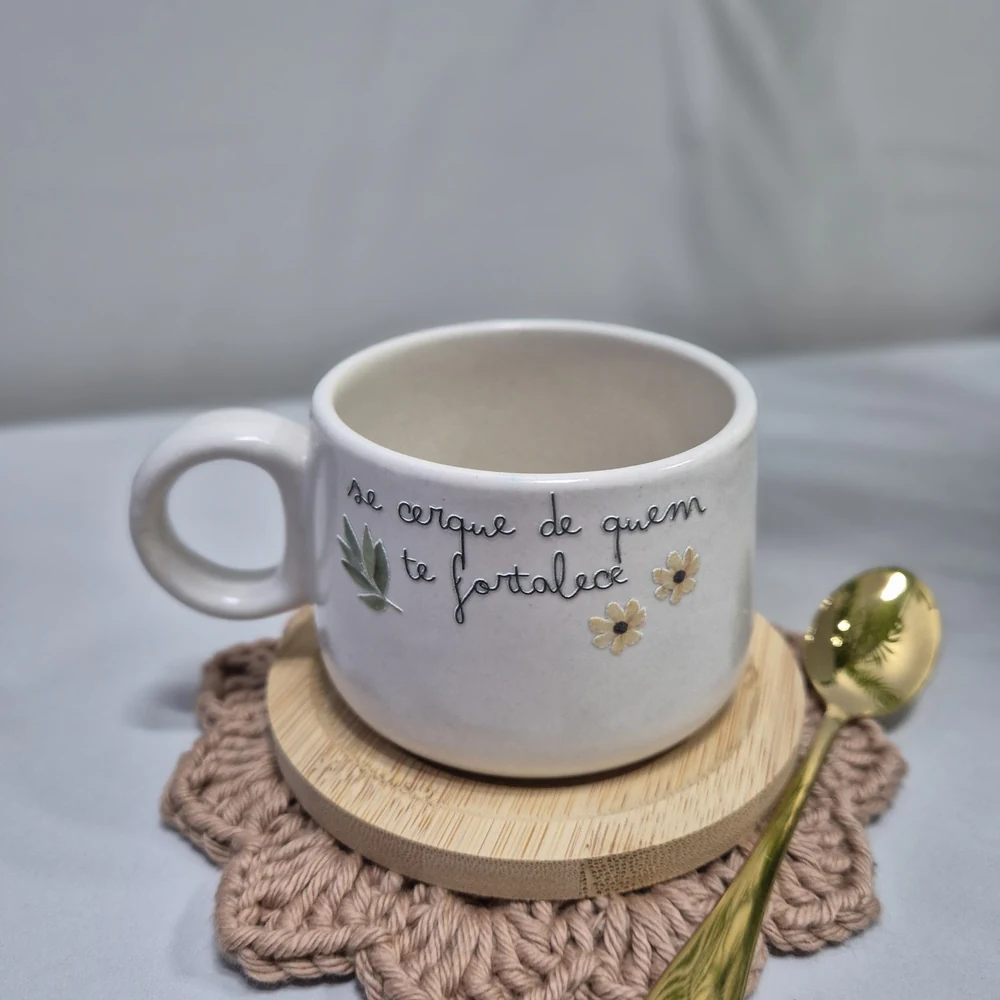 Caneca branca com frase personalizada, colher dourada e descanso de copo em crochê