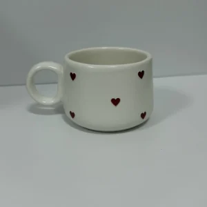 Caneca de cerâmica branca decorada com pequenos corações vermelhos