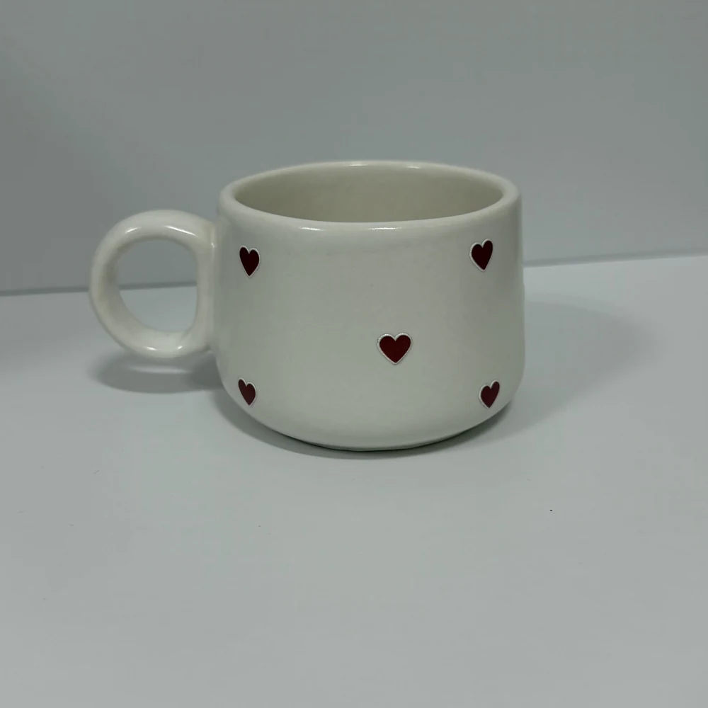 Caneca de cerâmica branca decorada com pequenos corações vermelhos