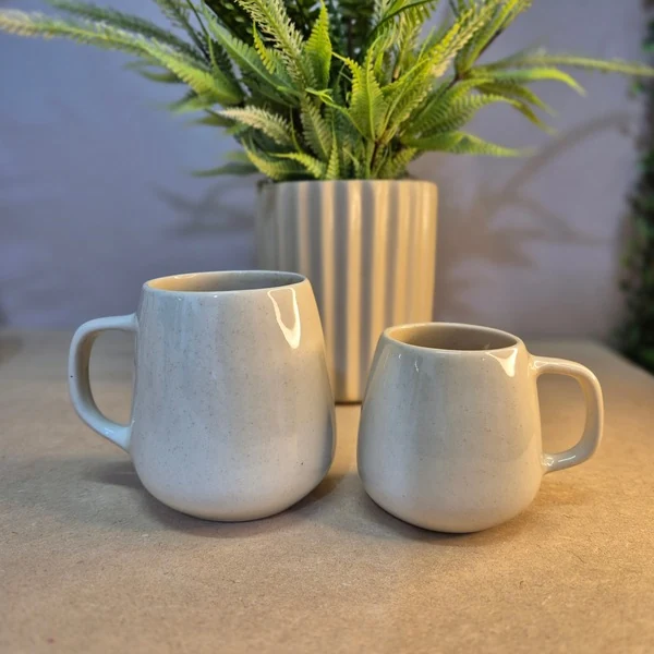 Duas canecas Orgânicas, de 150 ml e 260 ml, ao lado de um vaso canelado com planta